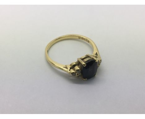 An 18ct gold ring set with possibly a sapphire and flanked by diamonds, approx 2.7g and approx size L.