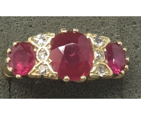 An 18ct gold ring inset with central band of three large rubies flanked by two rows of diamonds.Approx M/N