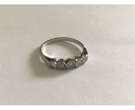 A White metal ring set with a row of five old cut diamonds. Ring size K-L