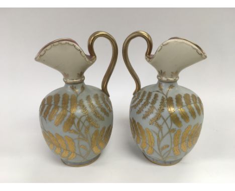 A pair of decorative ceramic jugs with giltwork leaf decoration on a light blue ground, approx 16.5cm.