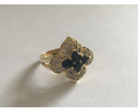 An 18 carat Gold blue sapphire and diamond ring with a clustered geometric pattern.