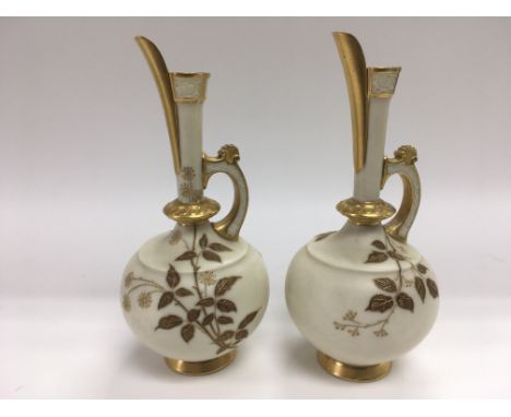 A pair of Royal Worcester jugs with giltwork decoration on an ivory ground, approx 13.5cm.