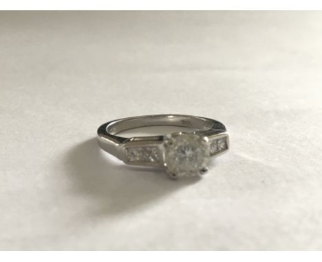 An 18 carat white gold ring set with a central diamond approximately.60 of a carat flanked by further small diamonds. Ring si