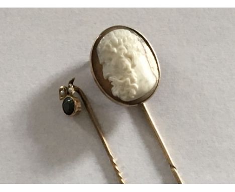 Two stick pins inset with a cameo and one other with a green stone and seed pearl. (2)