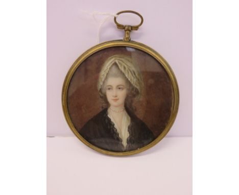 GEORGIAN PORTRAIT MINIATURE, a brass circular framed pendant miniature portrait of fashionable young lady with pearl necklace