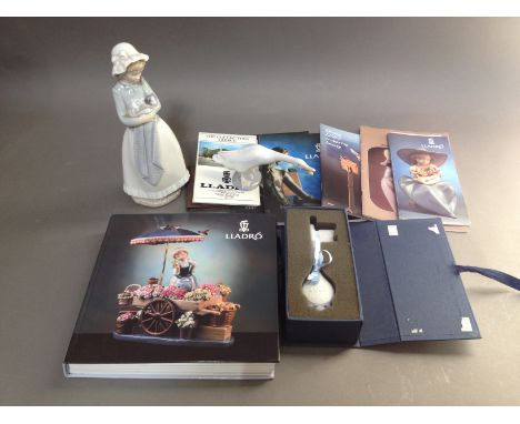 A mixed lot comprising a Nao figure, a Lladro key and a Lladro goose, together with assorted Lladro pamphlets and a book.  