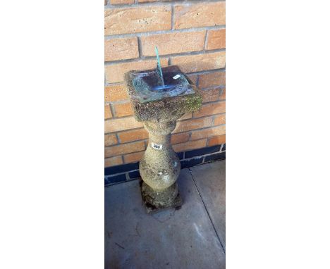 A concrete sundial with brass face