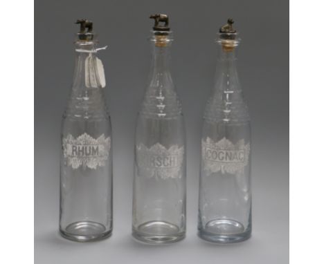 Three glass decanters, etched with Rhum, Kirsch and Cognac, with metal stoppers modelled as buffalo(2) and leopard