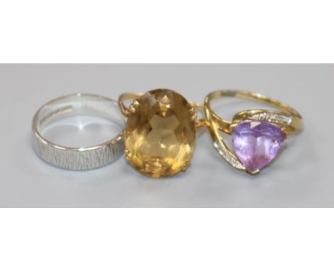 A 9ct gold and citrine dress ring, a 9ct white gold band and a yellow metal and amethyst ring.