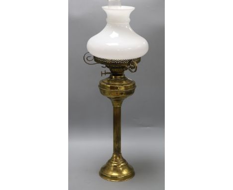 A Victorian brass reeded column oil lamp, on circular foot, with compressed spherical reservoir and opaque white glass shade,