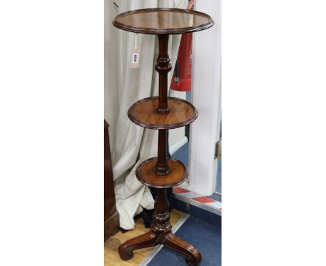 A late Victorian mahogany three tier dumb waiter, on turned partly reeded support, on scrolled tripod base, H.110cm