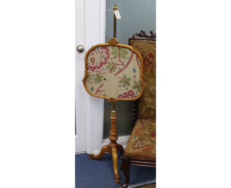 A Victorian maple pole firescreen, with adjustable brass tubular stem on reeded tripod base, supporting a cartouche shaped gl