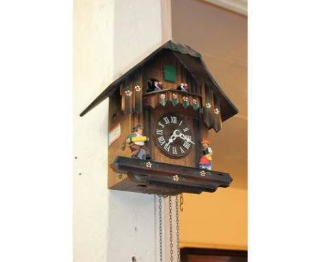 A 20th century carved wood cuckoo wall clock, with Swiss movement, decorated with painted figures, four weights, 29cm