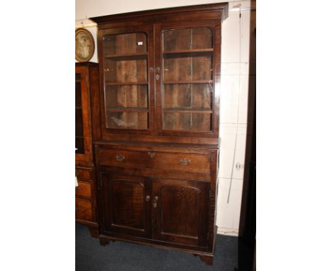 A 19th century oak bookcase, the top with twin glazed doors enclosing three shelves, above drawer and panelled cupboards on b