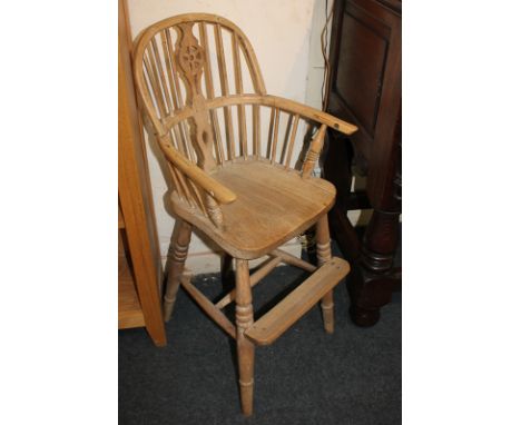 A child's Windsor style high chair with wheel and stick back, on turned legs with uniting stretcher and footrest 