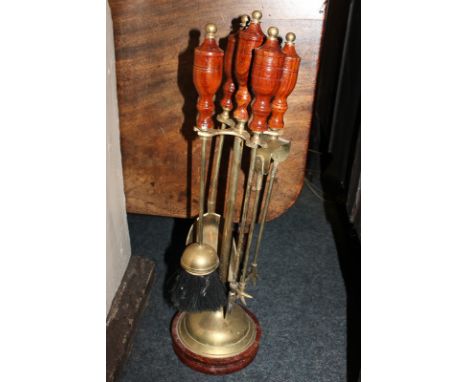 A set of four brass fire tools on stand with turned wooden handles and base