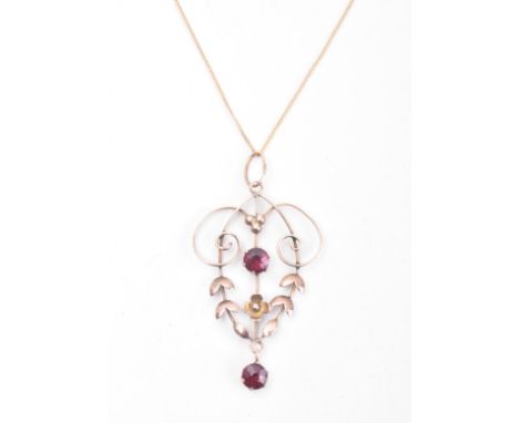 An antique 9ct gold and garnet necklace pendant on a 375 marked chain. The pendant of open work scrolling floral and foliate 