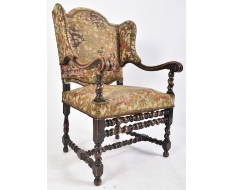 A 19th century French Louis XIV style oak framed wing back tapestry armchair. The arm chair having a shaped studded wing back