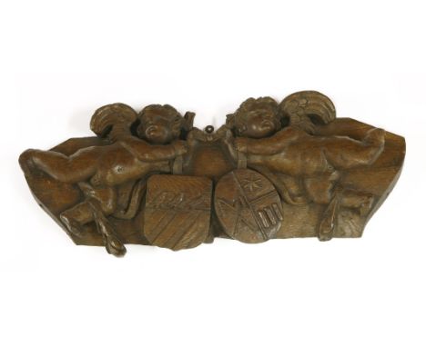 An oak panel,probably 18th century, carved with two angels holding a coat of arms,45cm longProvenance:  The Collection of Mr 
