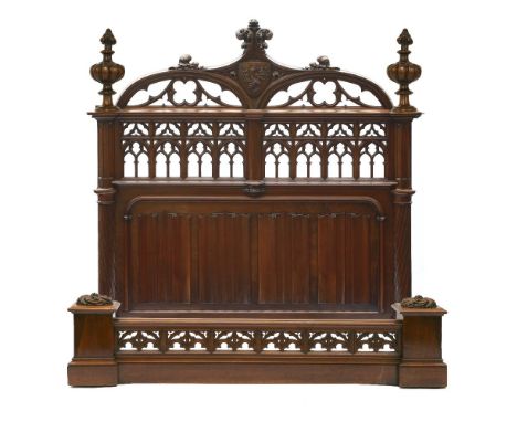 An extraordinary French Gothic walnut double bed,late 19th century, the headboard with a scrolled crest and coat of arms over