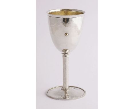 A modern silver goblet, M A B, London, 1987,the hammered funnel-shaped bowl with an everted rim set over a single gilt pellet