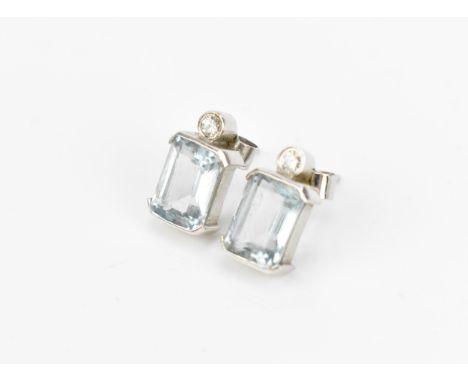 A pair of 9ct white gold, diamond and aquamarine earrings, set with central step cut aquamarine below a bezel set brilliant c