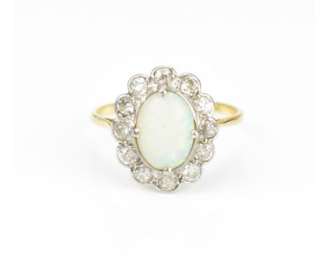 An 18ct gold, opal and diamond cluster ring, set with central oval cabochon white opal in a halo of twelve bezel set old cut 