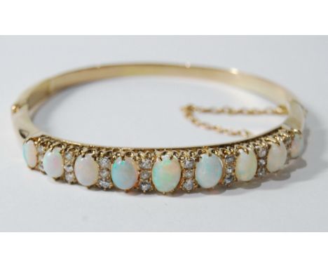 Edwardian gold hinged bangle with nine oval graduated opals separated by old-cut diamond brilliants in threes. Condition Repo