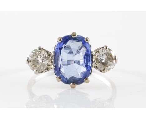 A SAPPHIRE AND DIAMOND THREE STONE RINGFeaturing a central oval blue sapphire (weight 3.05 carats), in a claw setting, with a