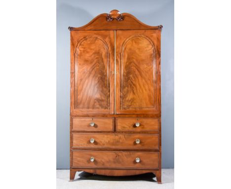 A George III Gentleman's Mahogany Wardrobe, the shaped pediment with four turned paterae, fitted three sliding trays enclosed