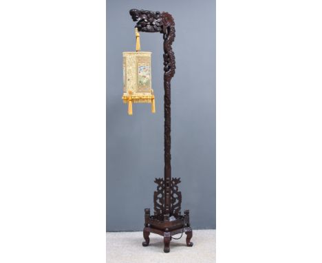 A Chinese Hardwood Standard Lamp, the whole boldly carved in the form of a dragon, supporting a lantern, on conforming base w