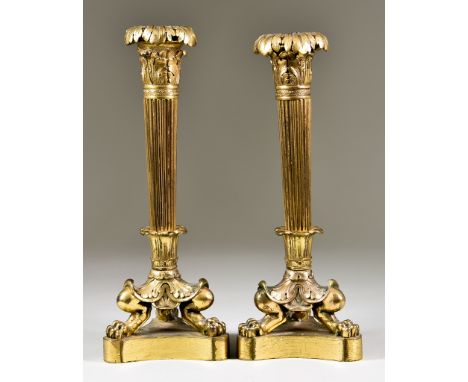 A Pair of Cast Gilt Brass Pillar Candlesticks of Empire Design, the triangular base and paw feet supporting a reeded column, 