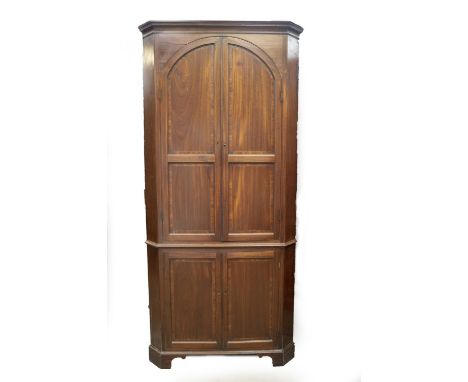 A George III mahogany standing corner cupboard, with moulded cornice and two double panelled arch doors with boxwood stringin