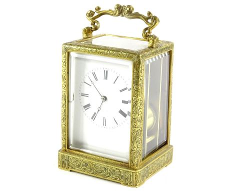 A late 19thC French brass carriage clock, elaborately engraved with foliate scrolls etc., with a white enamel dial, striking 