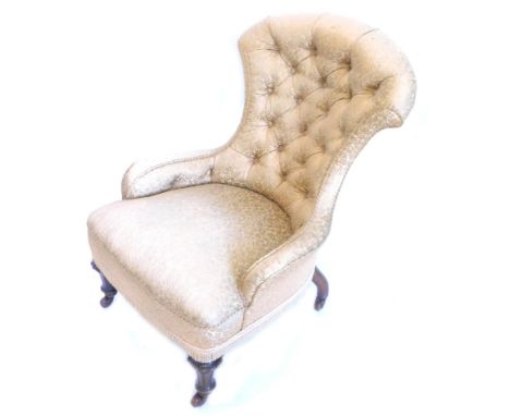 A Victorian ebonised nursing chair, with a buttoned back and padded seat, upholstered in gold damask type fabric, on turned f