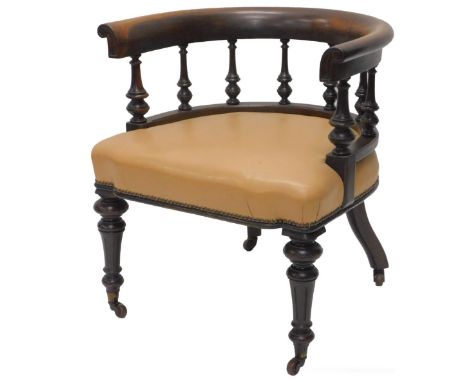 A Victorian walnut tub shaped library chair, with spindle turned supports, upholstered in beige leather, on turned fluted leg