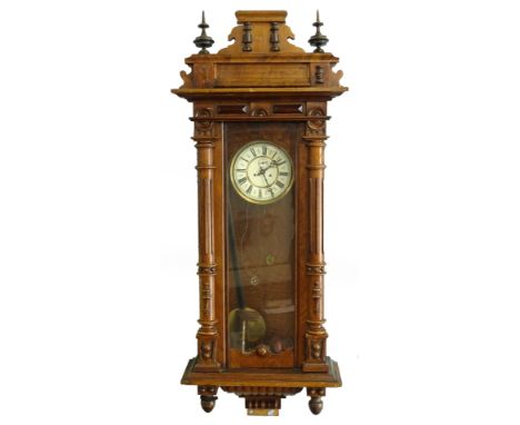 A late 19th/early 20thC Vienna walnut wall clock, with a shaped crest, fluted part turned pilasters and drop finials, the ena