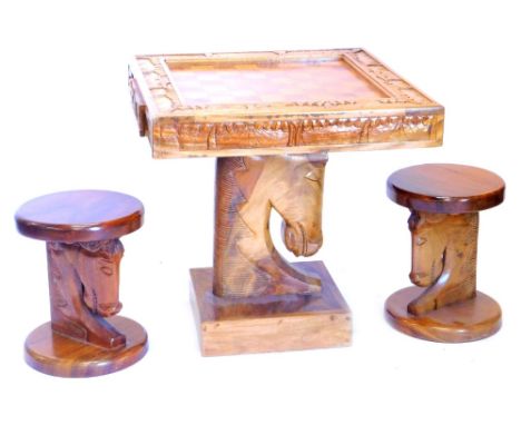 An African hardwood chess table, the square top inlaid with the board and a border carved with palm trees, buildings etc., ab