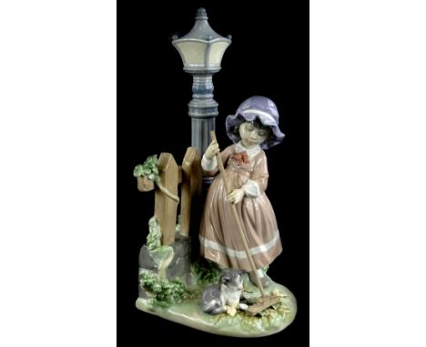 A Lladro porcelain figure group, depicting a girl raking leaves beside a lamp post, with a cat, 33cm H.