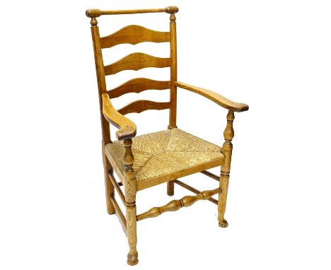 A 19thC ash ladder back chair, with a turned rail, shaped arms and rush seat with turned tapering legs and pad feet.