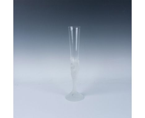 A clear glass with a frosted stem featuring the faces of seven women intertwined and flowing to the base. Erte engraved at ba
