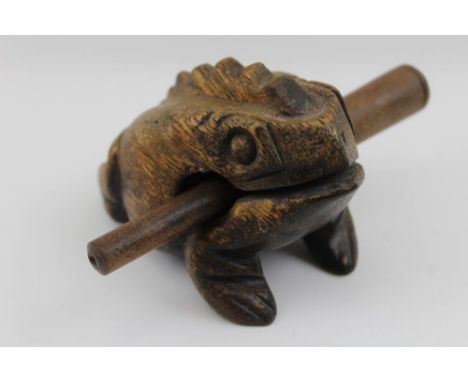 An early 20th century Far Eastern carved wood musical toad of guiro form, complete with wooden stick to rake across the spine