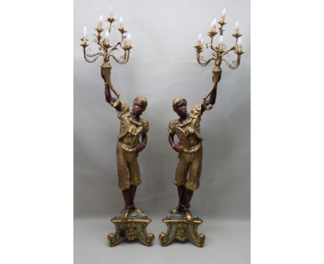 A pair of 20th century Blackamoor standard lamps, supporting decorative brass ten light electroliers, raised on triangular pl