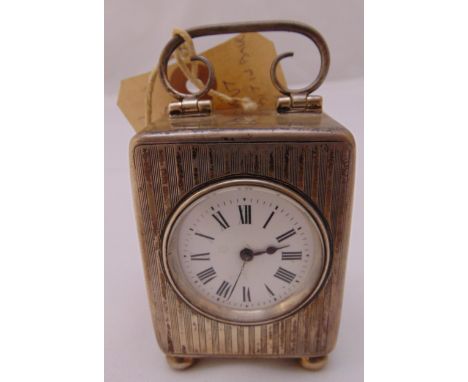 A rectangular hallmarked silver carriage clock, engine turned, white enamel dial and Roman numerals with scroll pierced carry