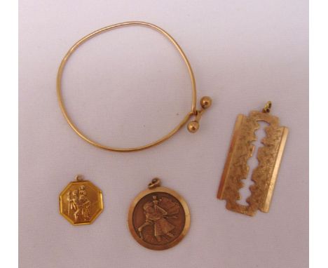 A quantity of 9ct gold jewellery to include a bangle, two Saint Christopher pendants and a pendant in the form of a razor bla
