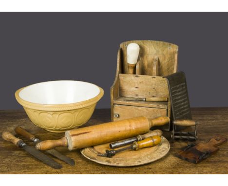 A selection of kitchenalia, including a ‘Want Not’ carved circular breadboard; a mandolin; a spoon rack with cupboard beneath