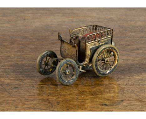 A gilt brass horseless carriage automobile tape measure, with red-painted tinplate upholstered seat, white rubber tyres and s