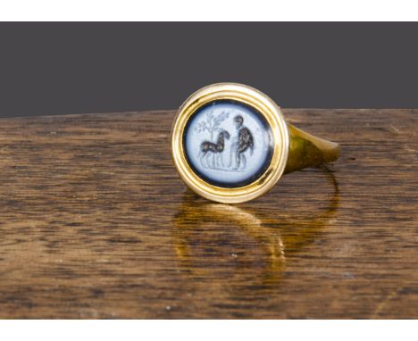An early 19th Century sard onyx intaglio signet ring, carved with fable of old man and donkey, in yellow metal 