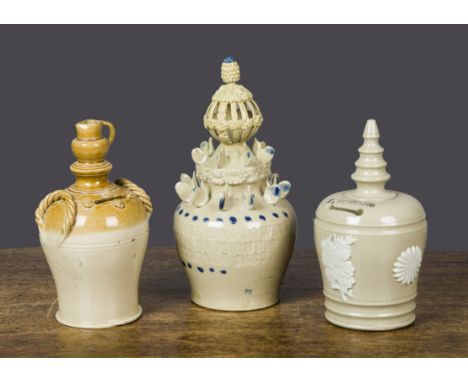 Three salt-glazed money banks, one buff and treacle glazes, the finial modelled as a jug —6¾in. (17cm.) high; a buff example 