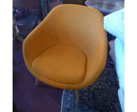 A Modernist style armchair upholstered in orange fabric, raised on light oak supports 